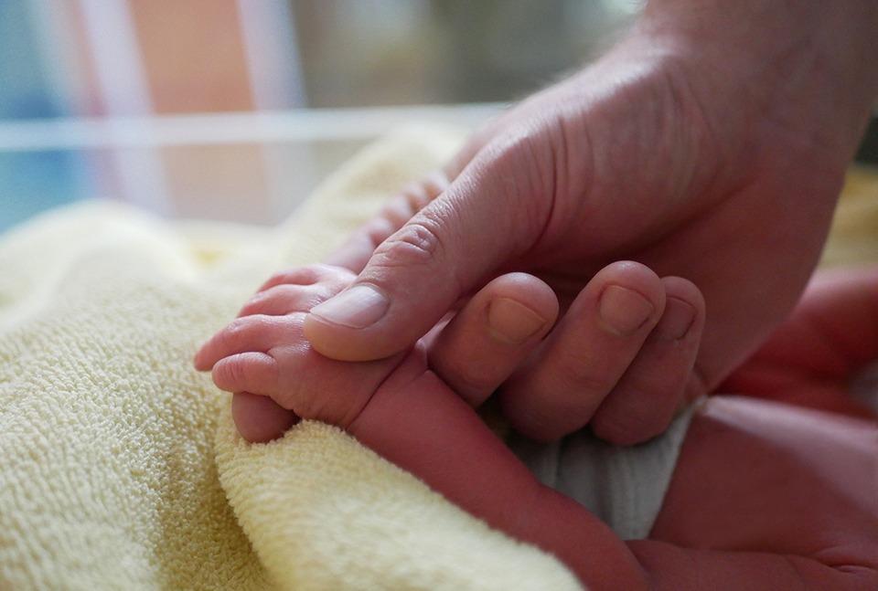 Vater hält Hand seiner neugeborenen Tochter – 1000. Geburt 2026
